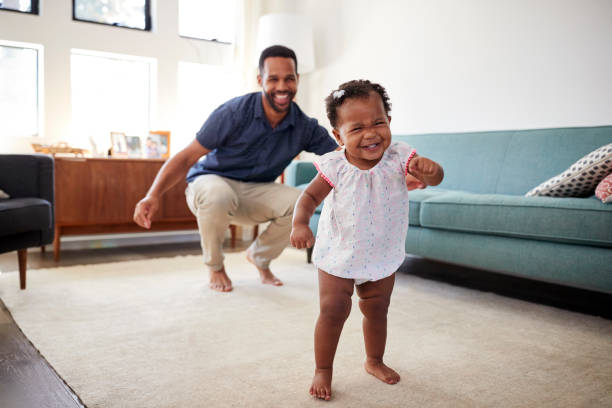 Baby Daughter Dancing With Father In Lounge At Home